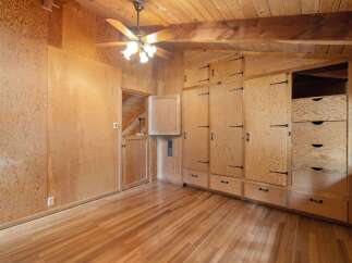 Step into this charming room featuring warm wood paneling and a sloped ceiling with exposed beams, creating a cozy and rustic ambiance.