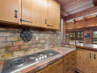 This rustic kitchen features a charming brick backsplash and a built-in electric stovetop, perfect for a cozy home.