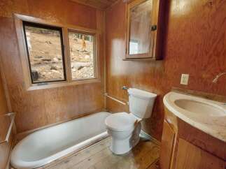This rustic bathroom features a classic white bathtub and a modern toilet, perfect for a cozy cabin retreat.