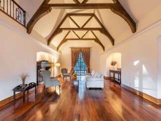 Experience luxurious living in this grand living room, featuring a stunning vaulted ceiling with exposed wooden beams and a charming fireplace.