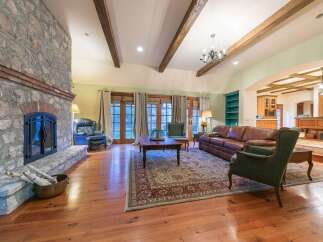 Step into this inviting living room featuring a grand stone fireplace and exposed wooden beams that add rustic charm.