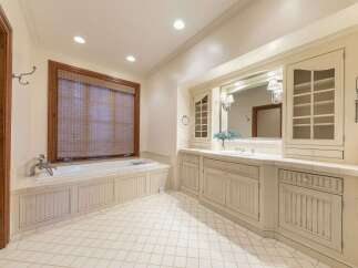 This elegant bathroom features a spacious soaking tub with a bamboo blind-covered window, offering a serene bathing experience.