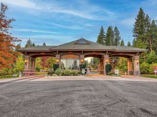 Welcome to a prestigious gated community, beautifully framed by vibrant autumn foliage and towering pine trees.