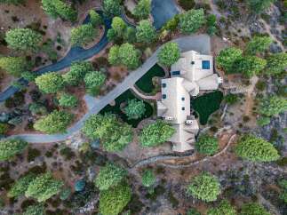 Experience luxury living in this stunning aerial view of a sprawling estate nestled amidst lush greenery.