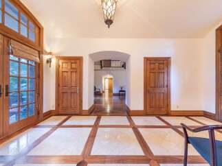 Step into this elegant entryway featuring a striking marble and wood inlay floor, creating a grand first impression.