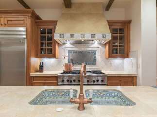 This luxurious kitchen boasts a professional-grade stainless steel range with a decorative tile backsplash and a custom range hood.