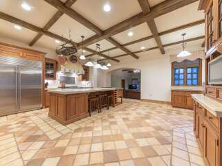 Experience luxury in this spacious kitchen featuring a large central island with seating and a pot rack overhead.