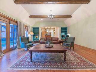 Step into this inviting living room featuring a vaulted ceiling with exposed wooden beams and a charming chandelier.