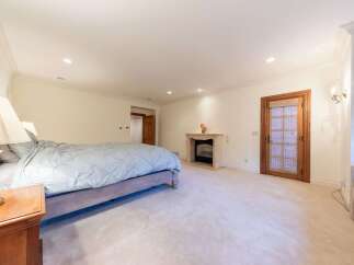 This spacious bedroom features a luxurious king-size bed with a light blue comforter, complemented by a classic wooden nightstand and lamp.