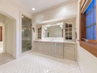 This spacious bathroom features a luxurious glass-enclosed shower and a long vanity with ample storage.
