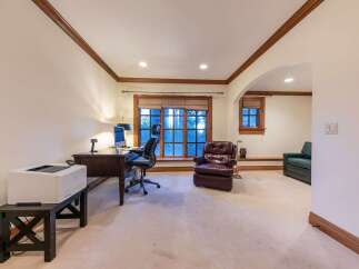 This home office features a dark wood desk with a computer and an ergonomic chair, complemented by a plush leather armchair.