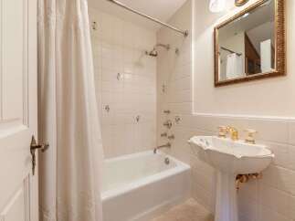 This charming bathroom features a classic white bathtub with a decorative floral shower curtain, perfect for a relaxing soak.