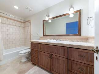 This bathroom features a classic design with a white bathtub and toilet, complemented by beige tiled walls and a decorative mosaic tile backsplash.
