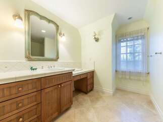 This charming bathroom features a spacious vanity with ample storage and a built-in makeup area, perfect for a functional and elegant space.
