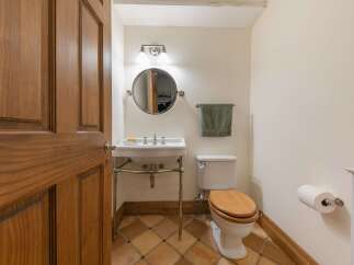 Step into this charming powder room, featuring a classic pedestal sink with chrome fixtures and a round mirror above.