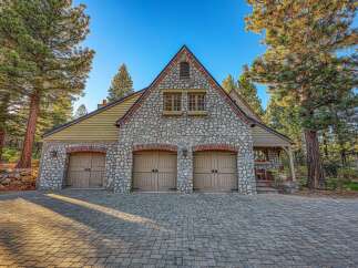 This stunning property boasts a charming stone-clad facade with three spacious garage doors, perfect for car enthusiasts or ample storage.