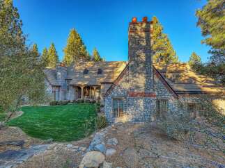 Discover this stunning stone-clad residence, featuring a prominent stone chimney with terracotta accents and a charming covered porch.