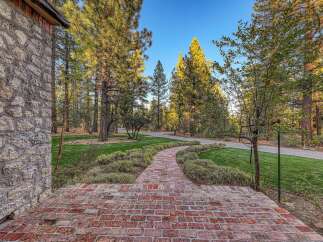 Step onto a charming brick pathway leading through a meticulously landscaped garden.