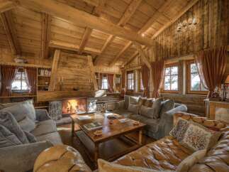 Experience ultimate comfort in this rustic living room, featuring a grand stone fireplace and exposed wooden beams.
