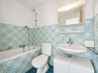 This bathroom features a classic design with charming teal and white patterned tiles adorning the walls.
