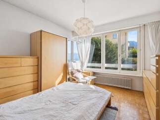Experience serene living in this charming bedroom, featuring a comfortable bed and ample storage with a large wooden dresser and a spacious wardrobe.