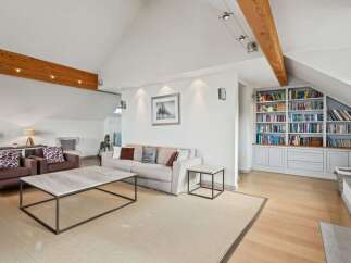 This spacious living room boasts a vaulted ceiling with exposed wooden beams and a modern track lighting system.