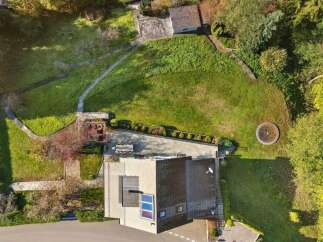 Discover this stunning aerial view of a modern home nestled within a lush, green landscape.
