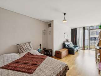 This studio apartment offers a cozy sleeping area with a decorative throw and a patterned pillow, perfect for relaxation.
