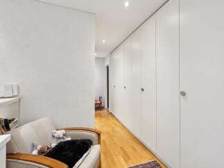 Discover this modern hallway featuring a long wall of sleek white built-in closets, offering ample storage.