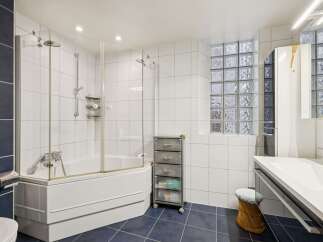 This bathroom features a spacious bathtub with a glass enclosure and a modern showerhead.