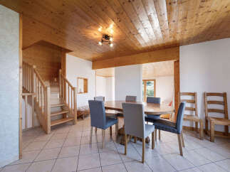 Experience rustic charm in this inviting dining area, featuring a warm wooden ceiling and a sturdy wooden staircase.