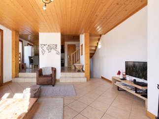 Step into this inviting living space featuring a warm wooden ceiling and a cozy brown armchair.