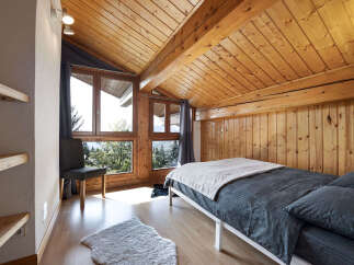 Experience cozy living in this charming attic bedroom, featuring a vaulted wooden ceiling and exposed beams that add rustic character.