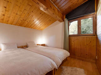 Experience cozy mountain living in this charming bedroom featuring two twin beds with crisp white linens, perfect for a restful night's sleep.