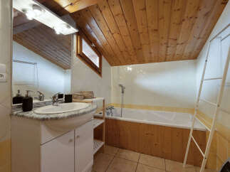 This charming bathroom features a spacious bathtub with a wooden paneling accent, perfect for a relaxing soak.