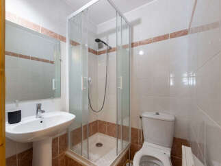 This bathroom features a modern shower enclosure with glass doors, a pedestal sink with a chrome faucet, and a toilet.