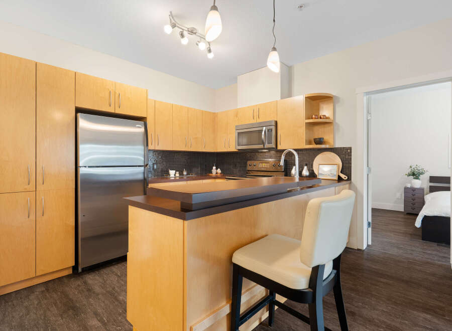 This modern kitchen boasts sleek, light wood cabinetry and a stainless steel refrigerator, offering ample storage and a clean aesthetic.