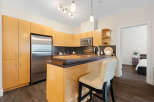 This modern kitchen boasts sleek, light wood cabinetry and a stainless steel refrigerator, offering ample storage and a clean aesthetic.