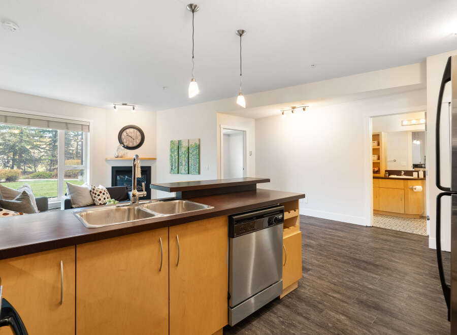 Experience modern living in this open-concept condo, featuring a sleek kitchen with a breakfast bar and stainless steel appliances.