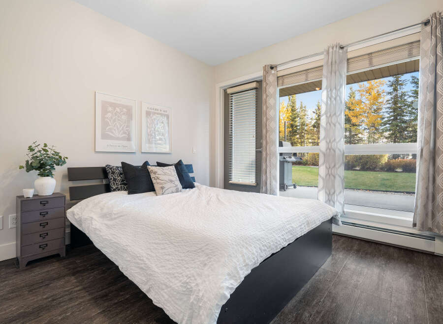 Experience comfortable living in this inviting bedroom, featuring a plush white comforter on a dark wood bed frame.