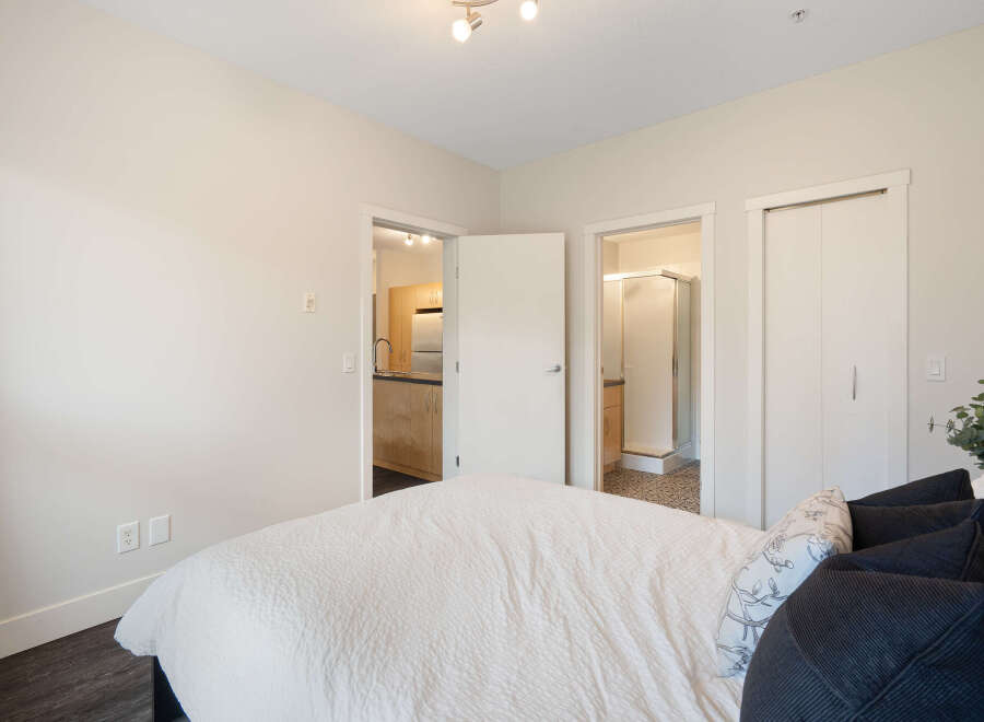 Step into this inviting bedroom, featuring a plush white comforter and a selection of decorative pillows.