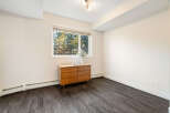 This room features a mid-century modern wooden dresser placed beneath a large window offering a view of lush trees.