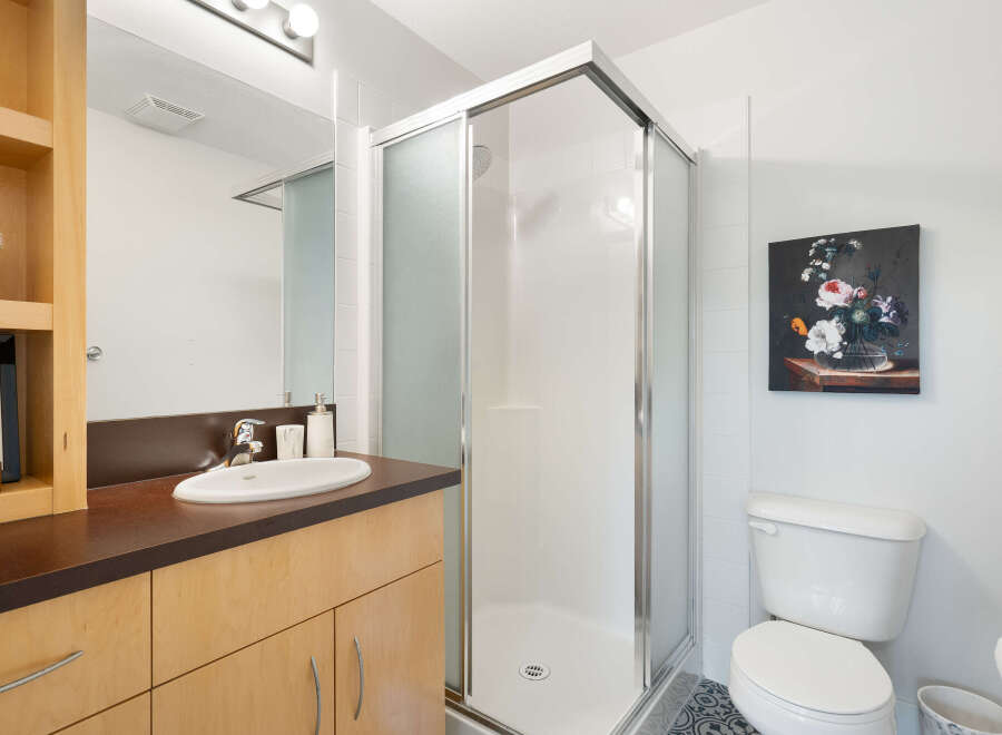 This modern bathroom features a sleek glass-enclosed shower and a stylish vanity with ample storage.