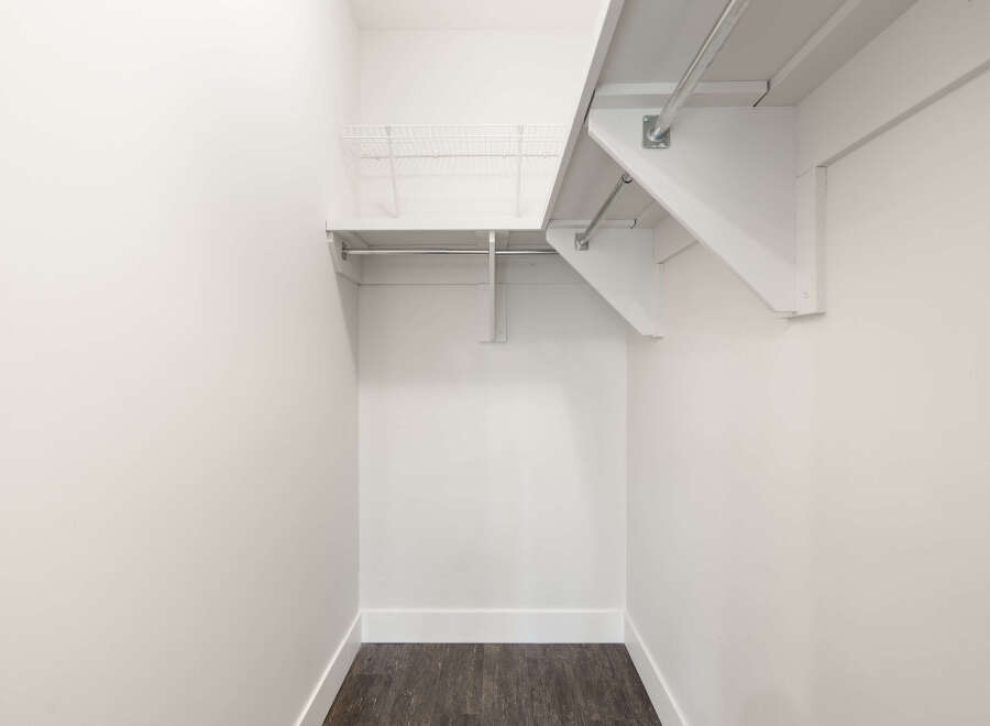 This spacious closet offers ample storage with a sturdy metal hanging rod and a wire shelving unit above.