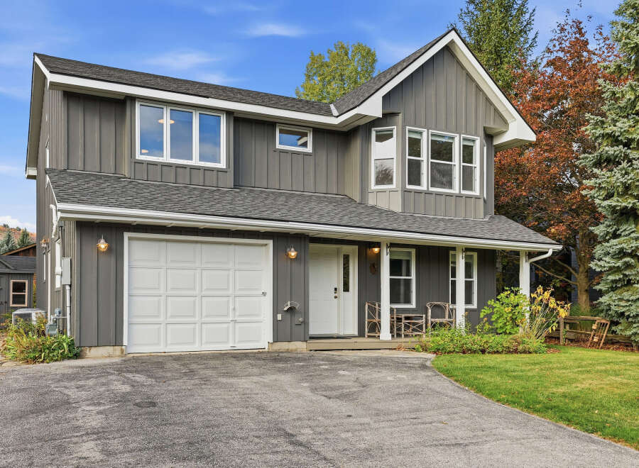 Discover this charming two-story home featuring a modern gray vertical siding exterior and a classic white garage door.