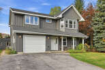 Discover this charming two-story home featuring a modern gray vertical siding exterior and a classic white garage door.