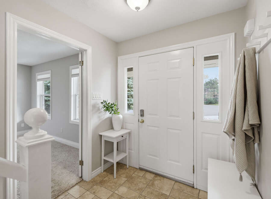Step into a welcoming foyer featuring a bright white door with glass accents, flanked by sidelights.