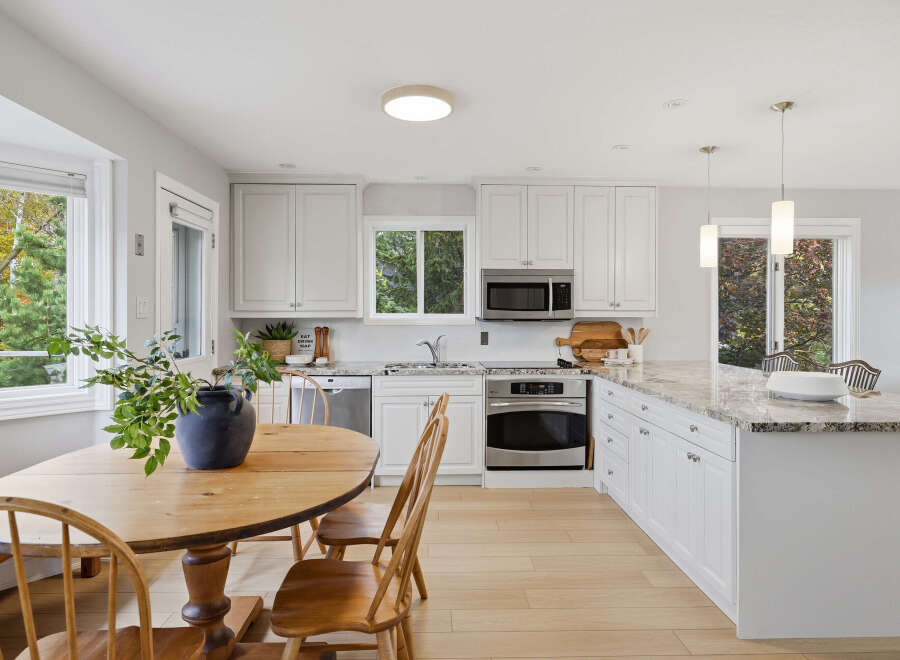 This bright and airy kitchen features crisp white cabinetry and a stunning granite countertop island, perfect for meal prep and casual dining.