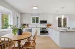 This bright and airy kitchen features crisp white cabinetry and a stunning granite countertop island, perfect for meal prep and casual dining.