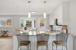 This spacious kitchen boasts a large granite island with comfortable seating, perfect for casual dining and entertaining.